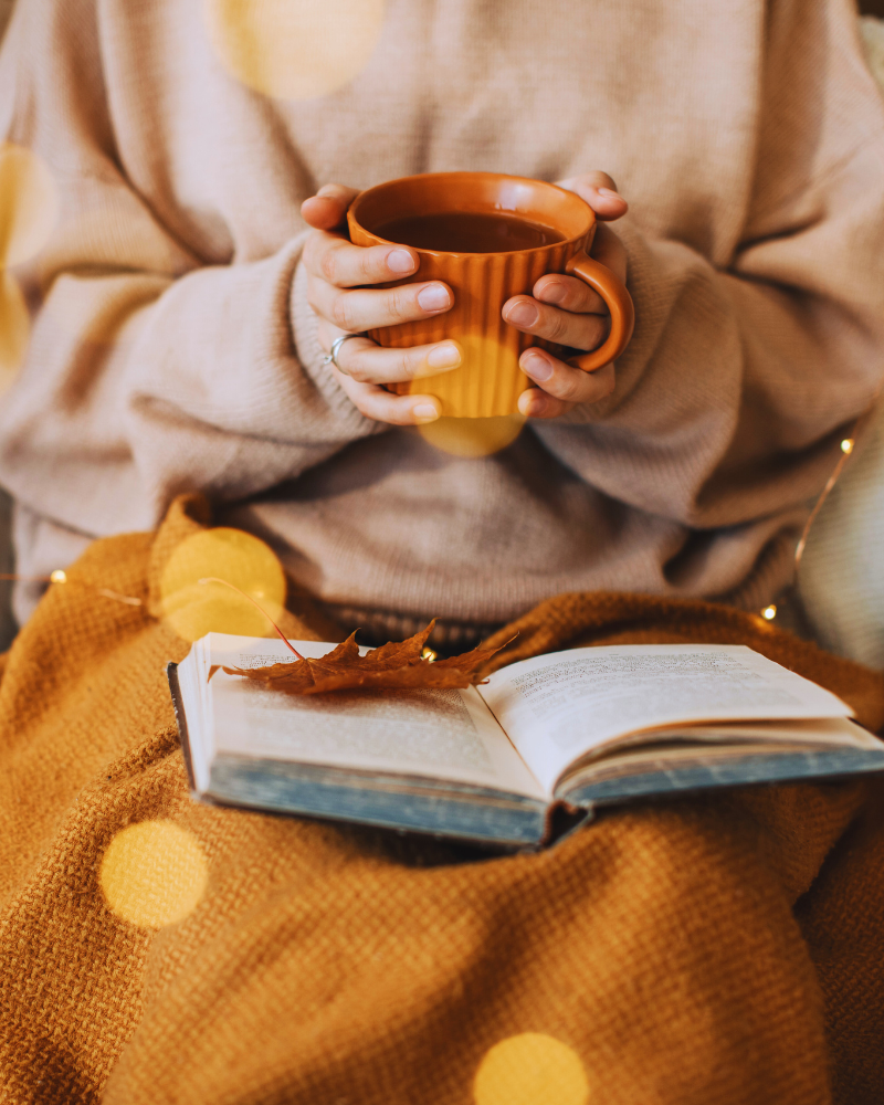 Woman in sweater with book and cup of coffee